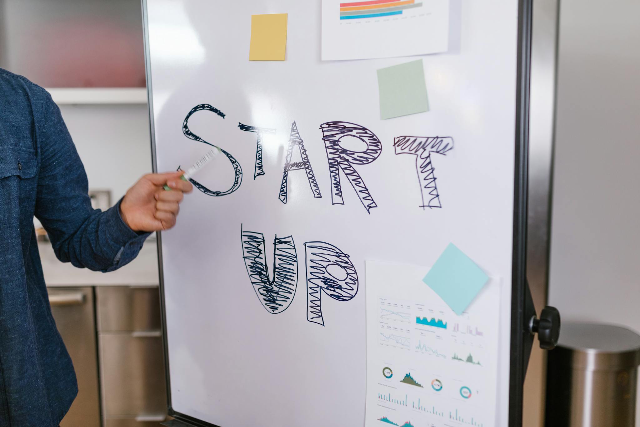 A person presents a startup idea on a whiteboard in an office setting, emphasizing entrepreneurship.